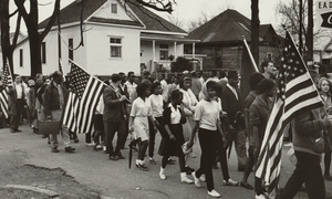 Historical image of marchers with American flags participating in the 1965 Selma to Montgomery march