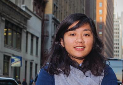 A student stands in front of a cityscape.
