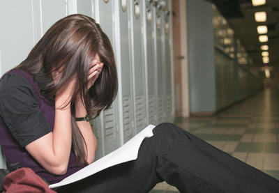girl reading with face in hands sitting on hallway floor