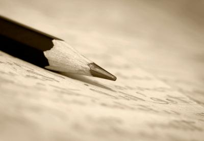 A pencil sitting on top of a sheet of paper with writing on it.