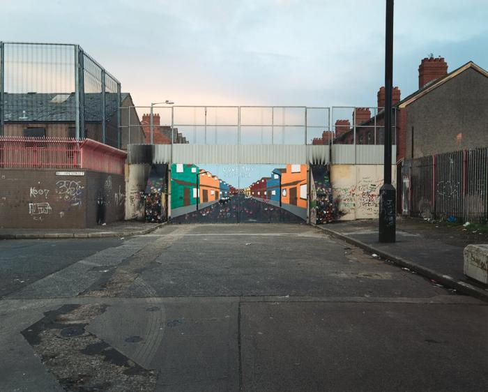 Gate painted as a continuation of the street with the sentence "LOVE THY NEIGHBOR"