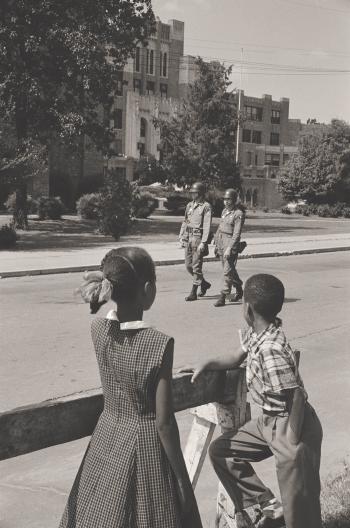 Two young children watch 2 National Guard Officials in front of the Central High School, September 1957